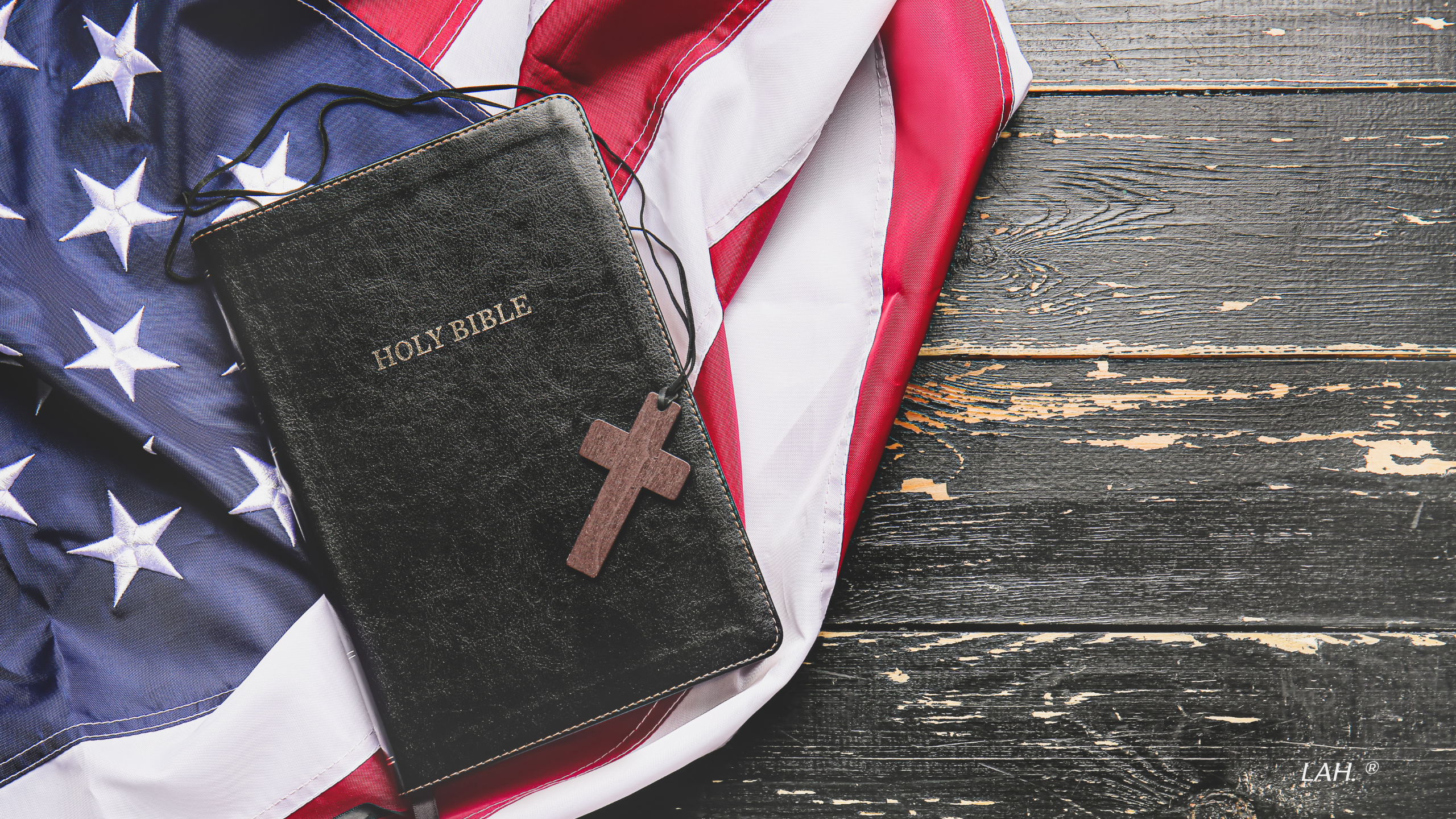 Black Bible with cross on an American flag on a wooden surface